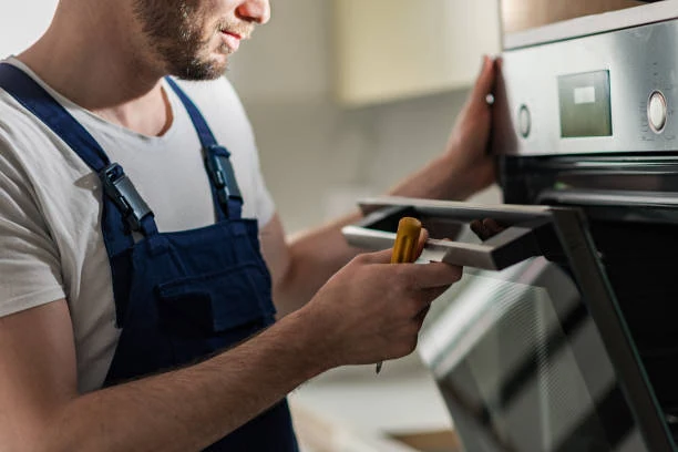Technician using a screwdriver to service an open oven door